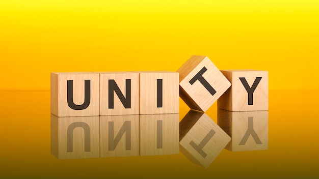 UNITY-Text auf Holzwürfeln, die von der leuchtend gelben Oberfläche reflektiert werden