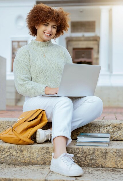 Universidade de laptop e retrato de uma mulher na cidade sentada na escada estudando para teste ou exame educação feliz e estudante universitária do brasil trabalhando em projeto acadêmico no computador