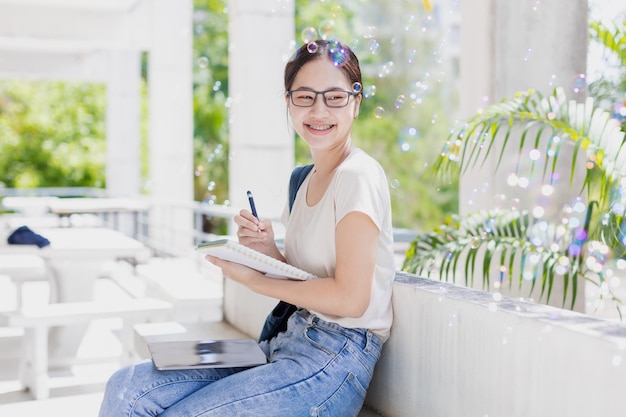 Universitäts-Teenager-Mädchen, glücklich lächelnd, genießen Sie das Lernen, Bildung, junge Frau, die Notiz-Tagebuch schreibt, gutes Gedächtnis