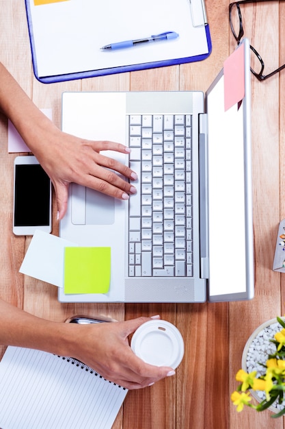 Unkosten der weiblichen Hände, die Laptop verwenden und Kaffeetasse halten