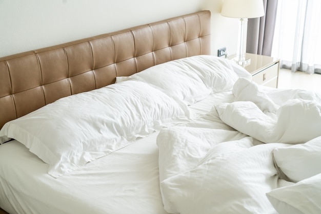 Unordentliches Bett mit weißem Kissen und Decke auf dem Bett