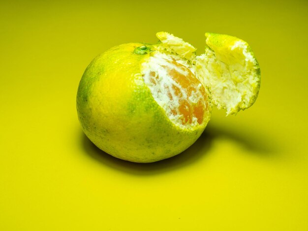 Unreife Mandarine auf gelbem Hintergrund Schälen einer Mandarine Grün und gelb Farbe Sauer