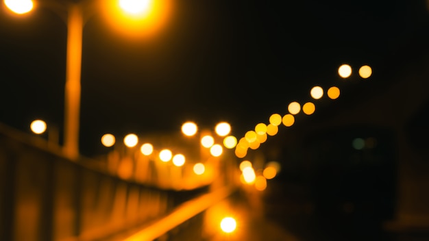 Unscharfe Brücke, Straße und elektrischer Pfosten mit dem Gelb verwischt in der Nacht. Nachtleben-Konzept. Gold und orange Bokeh von Lichtern in der Straße