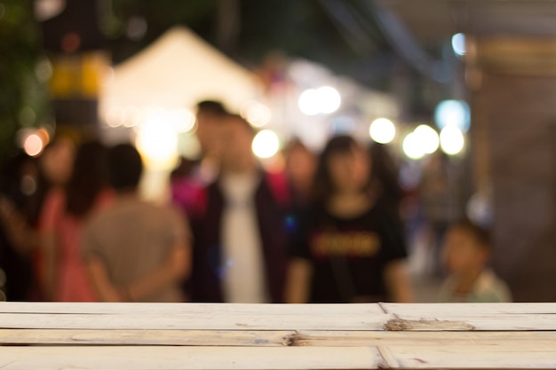 Foto unscharfe leute auf nachtstraße und hölzerner tischplatte auf guss