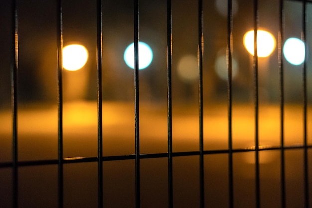 Unscharfe Lichter der Stadt hinter einem Zaun Bokeh Soft-Fokus Bunte Straßenlaternen der Nachtstadt