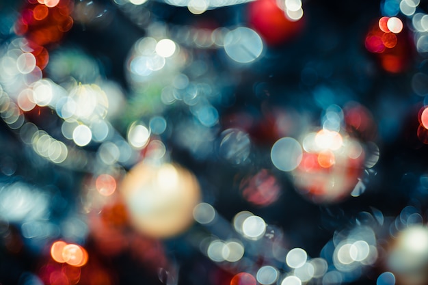 Unscharfe zusammensetzung mit deecorationbällen und hellen schnüren auf weihnachtsbaum mit bokeh licht