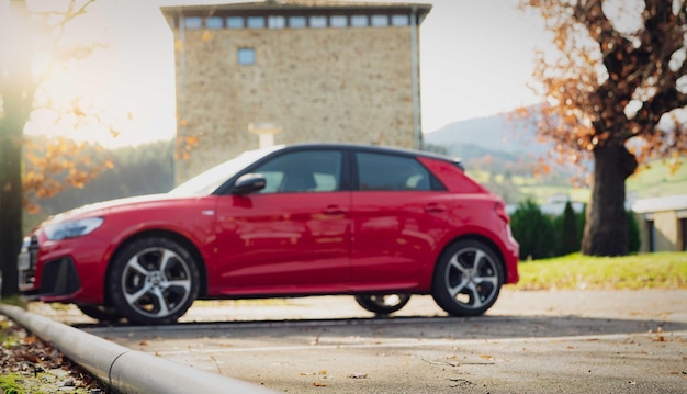 Unscharfer roter SUV, der auf dem Parkplatz im Freien der Stadt geparkt ist Seitenansicht des EV-Autos auf dem Parkplatz