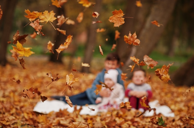 Unscharfes Foto der glücklichen Familie von drei Kindern im Herbstlaubpark.