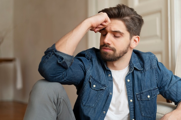 Foto unsicherer mann, der auf dem boden sitzt, mittlerer schuss