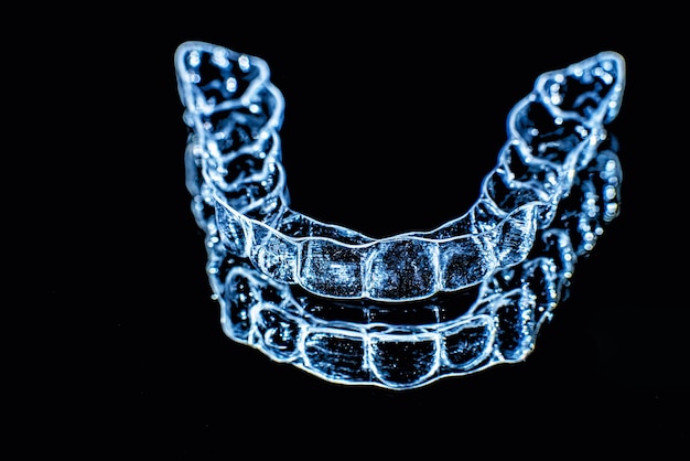 Foto unsichtbare zahnspangen zahnausrichter auf schwarzem hintergrund zahnmedizinische halterungen aus kunststoff für zahnspangen, um die zähne zu begradigen