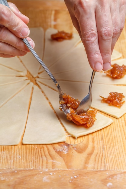 Untar mermelada con una cuchara sobre masa de croissant