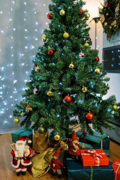 Foto unter dem weihnachtsbaum liegen bunte geschenke mit figuren von weihnachtsmann und elfen