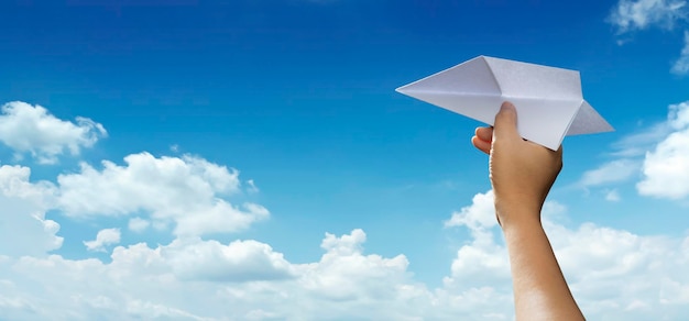 Foto unter flug hand wirft papierflugzeug gegen blauen himmel mit leerem platz für textgrafik