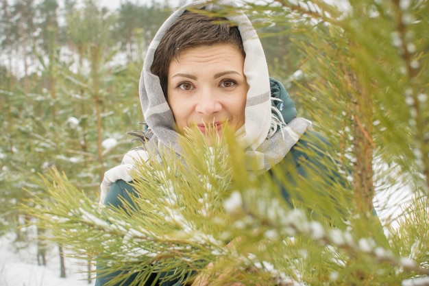 Unter Tannenzweigen im Winter lachende Frau