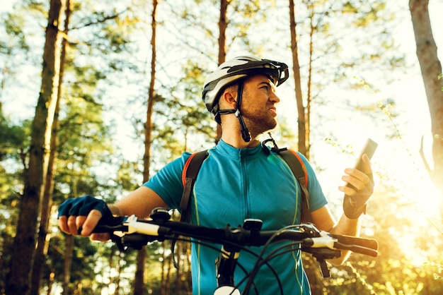 Unteransicht Außenaufnahme eines Radfahrers auf dem Fahrrad mit dem Navigator auf dem Smartphone Erkunden Sie die Karte und suchen Sie GPS-Koordinaten beim Radfahren in den Bergen Reisen Sie Sport, aktiven Lebensstil und moderne Technologie