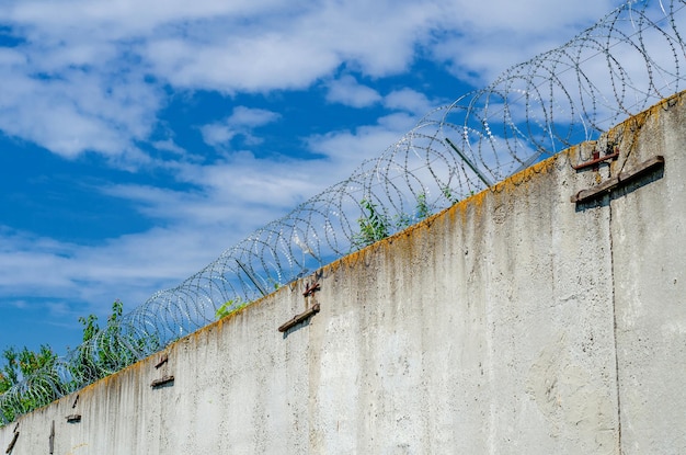 Unteransicht des Stacheldrahts an einer hohen Mauer Schutz eines wichtigen Objekts Betonwand