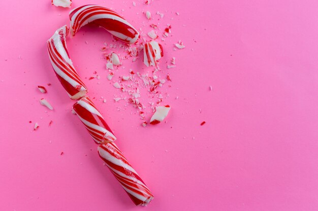 Unterbrochene Zuckerstange auf rosa Hintergrund.