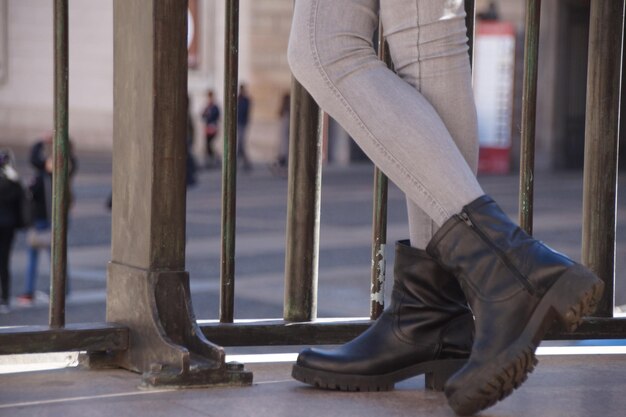 Foto unterer abschnitt einer frau in schwarzen schuhen am geländer