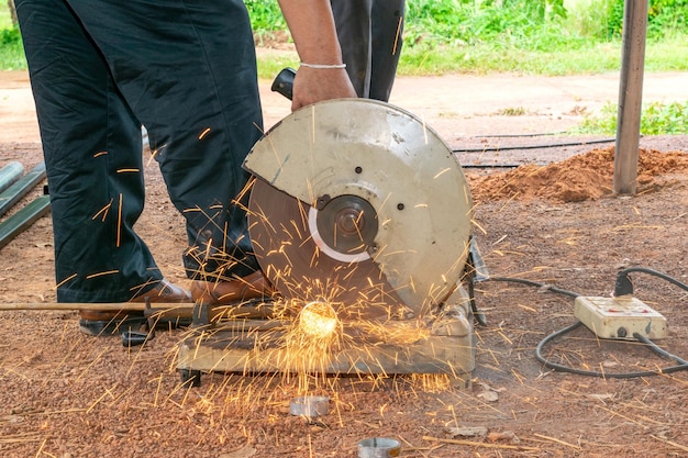 Unterer Abschnitt eines Mannes, der Metall mit einer Kreissäge auf der Baustelle schneidet
