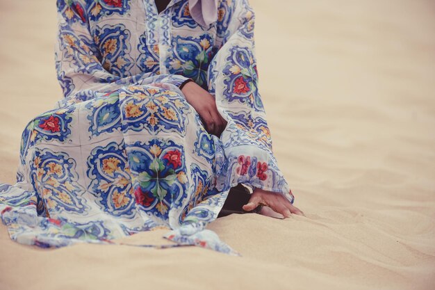 Foto unterer teil einer frau, die am sandstrand sitzt