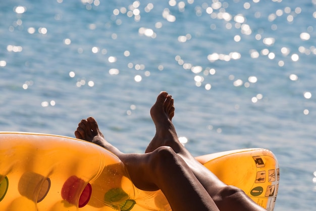 Foto unterer teil einer frau, die an einem sonnigen tag auf einem aufblasbaren floß am meer liegt