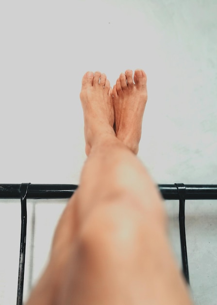 Unterer Teil einer Frau, die auf einem Bett an der Wand ruht
