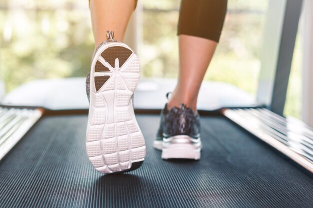 Foto unterer teil einer frau, die auf einem laufband im fitnessstudio läuft