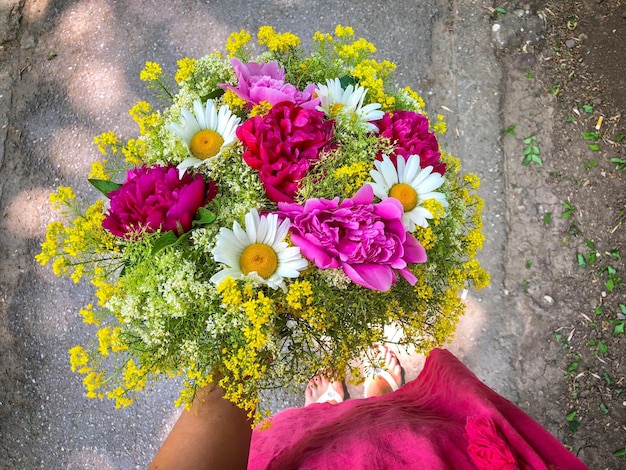 Foto unterer teil einer frau, die einen blumenstrauß hält