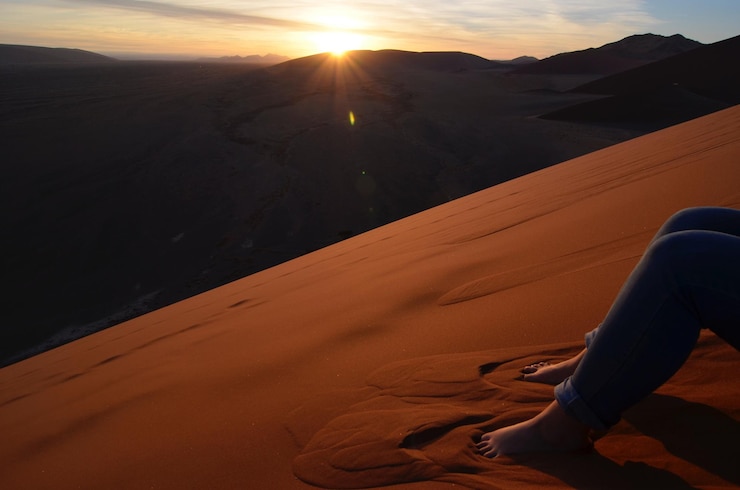 Foto unterer teil einer person auf dem sand bei sonnenuntergang