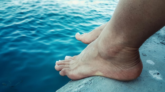 Unterer Teil einer Person, die am Ufer sitzt