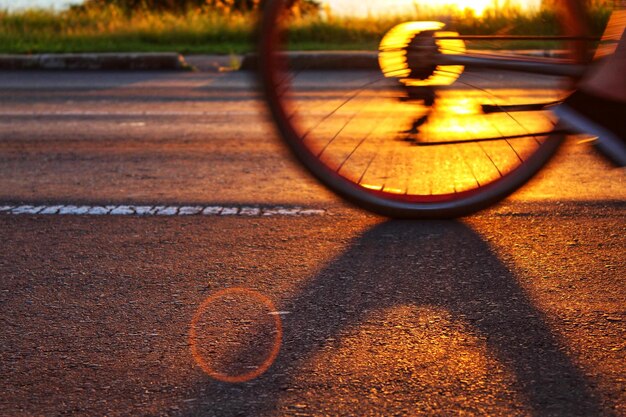 Foto unterer teil einer person, die bei sonnenuntergang mit dem fahrrad auf der straße fährt