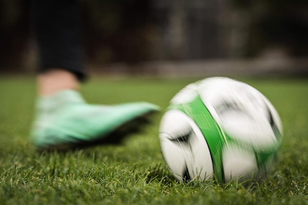 Unterer Teil einer Person, die einen Fußball auf dem Spielfeld tritt