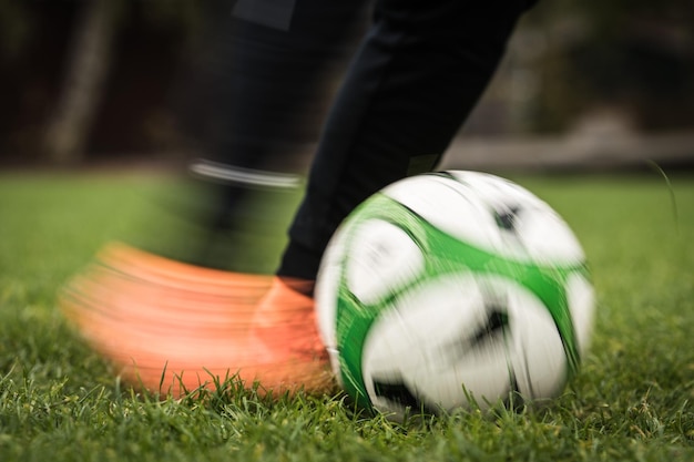 Unterer Teil einer Person, die einen Fußball auf dem Spielfeld tritt