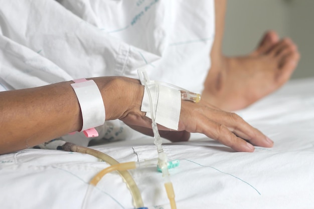 Foto unterer teil einer person mit intravenösen tropfen im krankenhausbett