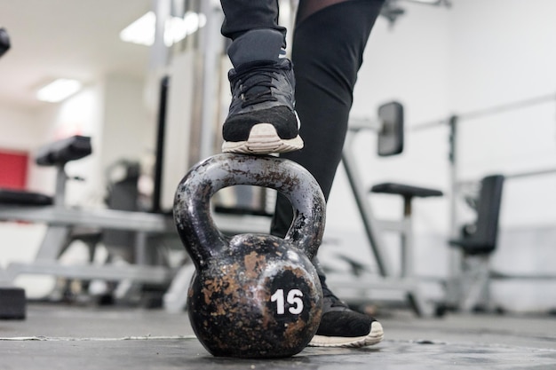 Unterer Teil einer Person mit Kettlebell, die im Fitnessstudio steht