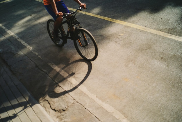 Unterer Teil eines Mannes, der auf der Straße Fahrrad fährt