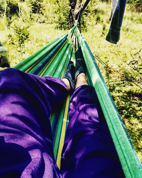 Unterer Teil eines Mannes, der auf einer Hängematte im Wald liegt