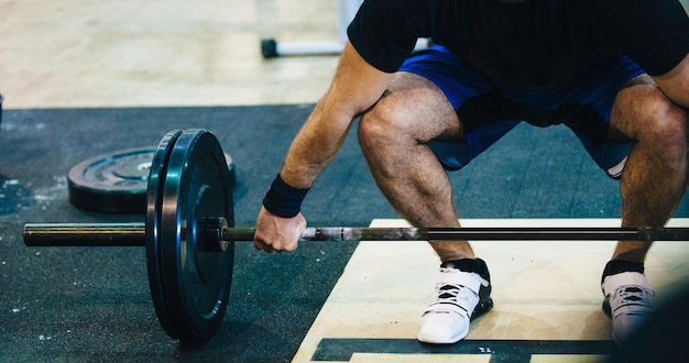 Foto unterer teil eines mannes, der eine barbell im fitnessstudio hält