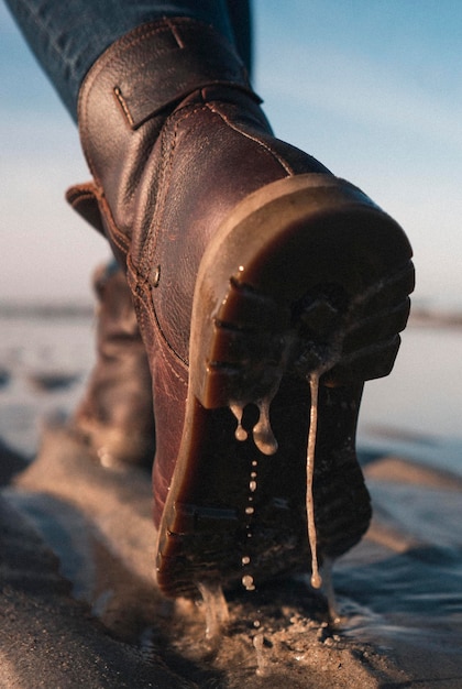 Foto unterer teil eines mannes, der schuhe am strand trägt