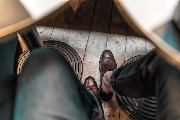 Unterer Teil eines Mannes, der Schuhe auf einem Holzboden trägt