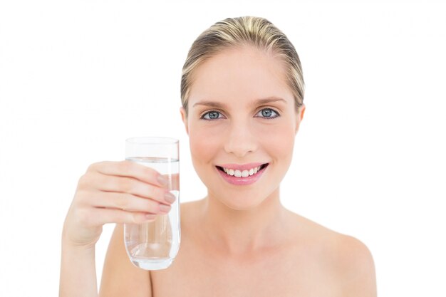 Unterhaltene frische blonde Frau, die ein Glas Wasser anhält