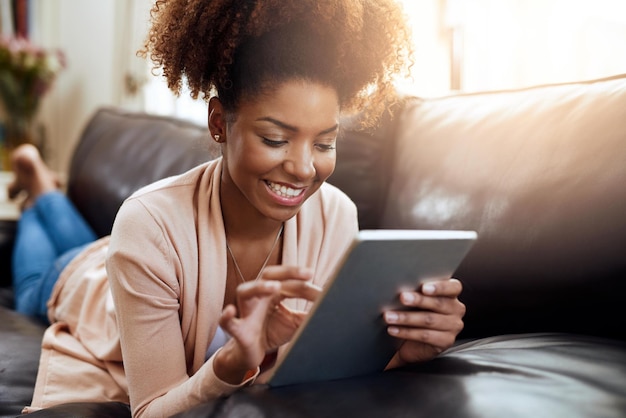 Unterhaltung für den Stubenhocker Aufnahme einer entspannten jungen Frau mit einem digitalen Tablet auf dem heimischen Sofa