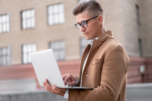 Unternehmen. Geschäftsmann mit Laptop im Freien Erwachsene kaukasische männliche Geschäftsperson Brillen beobachten Notebook-Bildschirm außerhalb ernsthaftes Denken Sonnenlicht Hintergrund Big City Street