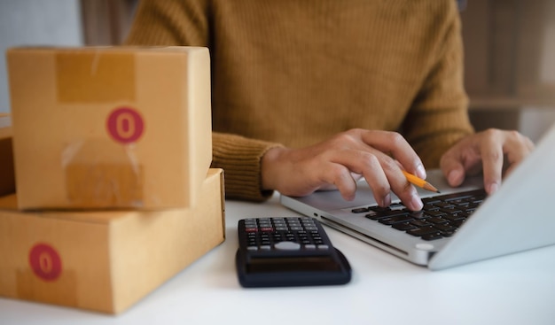 Unternehmer mit Taschenrechner mit Bleistift in der Hand Berechnung der finanziellen Ausgaben im Home Office Online-Markt Verpackungsbox LieferungStartup erfolgreiches KMU-Konzept für Kleinunternehmer