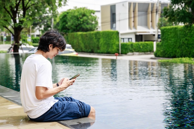 Unternehmer verbindet Arbeit und Freizeit im Urlaub mit Laptop am Swimmingpool