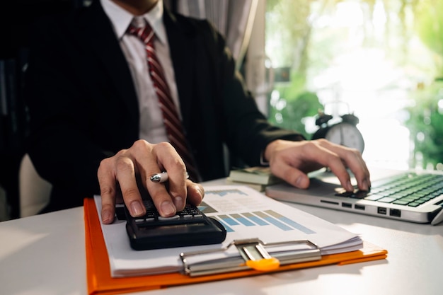 Unternehmerin, die einen Taschenrechner mit einem Stift in der Hand verwendet, um die finanziellen Ausgaben im Home Office zu berechnen