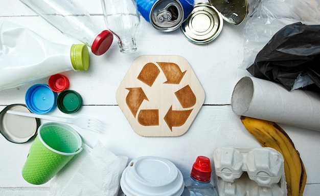 Unterschiedlicher Müll auf dem Tisch und Recycling-Symbol zwischen ihnen