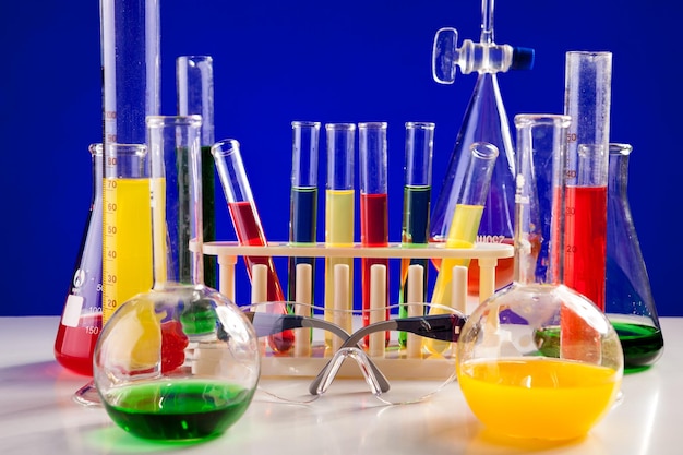 Unterschiedliches Chemielabor auf einem Tisch auf blauem Hintergrund. Glaswaren und Biologiegeräte