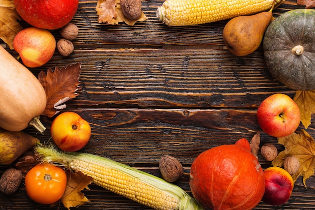 Unterschiedliches Gemüse, Kürbise, Äpfel, Birnen, Nüsse, Tomaten, Mais, trockenes Gelb verlässt auf hölzernem Hintergrund. Herbststimmung, copyspace. Ernte .