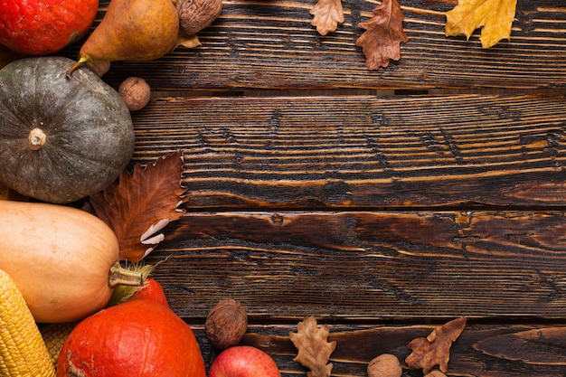 Unterschiedliches Gemüse, Kürbise, Äpfel, Birnen, Nüsse, Tomaten, Mais, trockenes Gelb verlässt auf hölzernem Hintergrund. Herbststimmung, copyspace. Ernte .